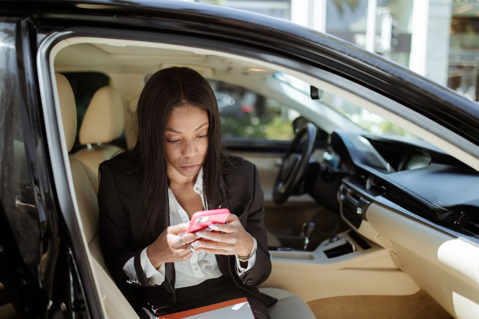 A businesswoman uses her smartphone while seated in a car, focusing intently on the screen. Mobile Notary Scheduling: Build a More Reliable Day