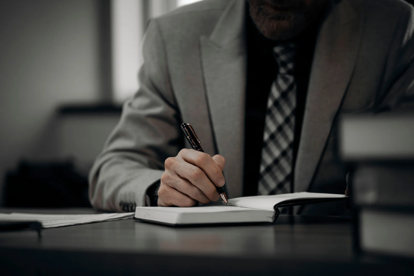 A professional businessman in a suit writing notes at a desk in a modern office environment, showcasing productivity. Sorting mobile notary complaints into three kinds and how to handle each