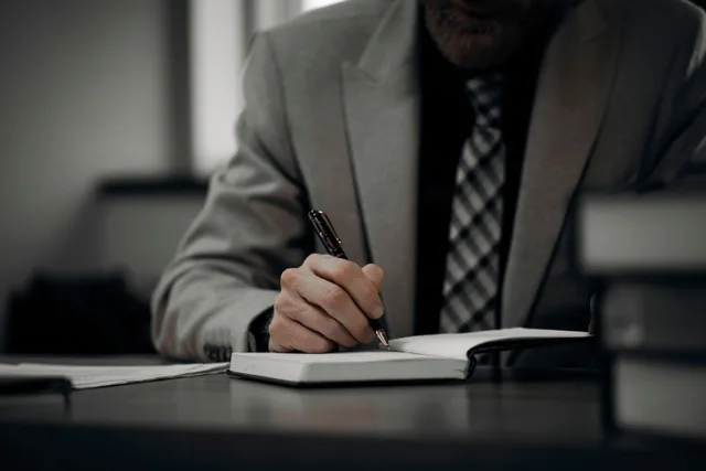 A professional businessman in a suit writing notes at a desk in a modern office environment, showcasing productivity. Sorting mobile notary complaints into three kinds and how to handle each