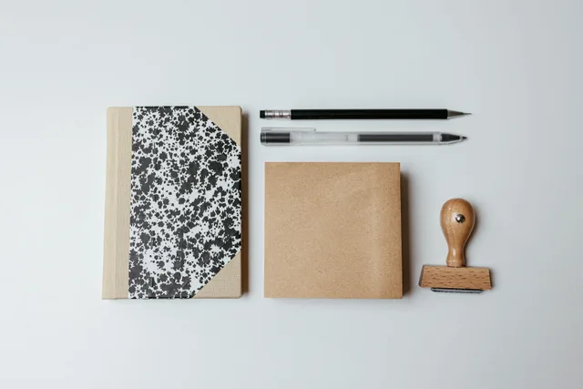 A modern flatlay featuring a notepad, pens, and a wooden stamp on a clean background. Mobile notary employee training: what to watch at the table