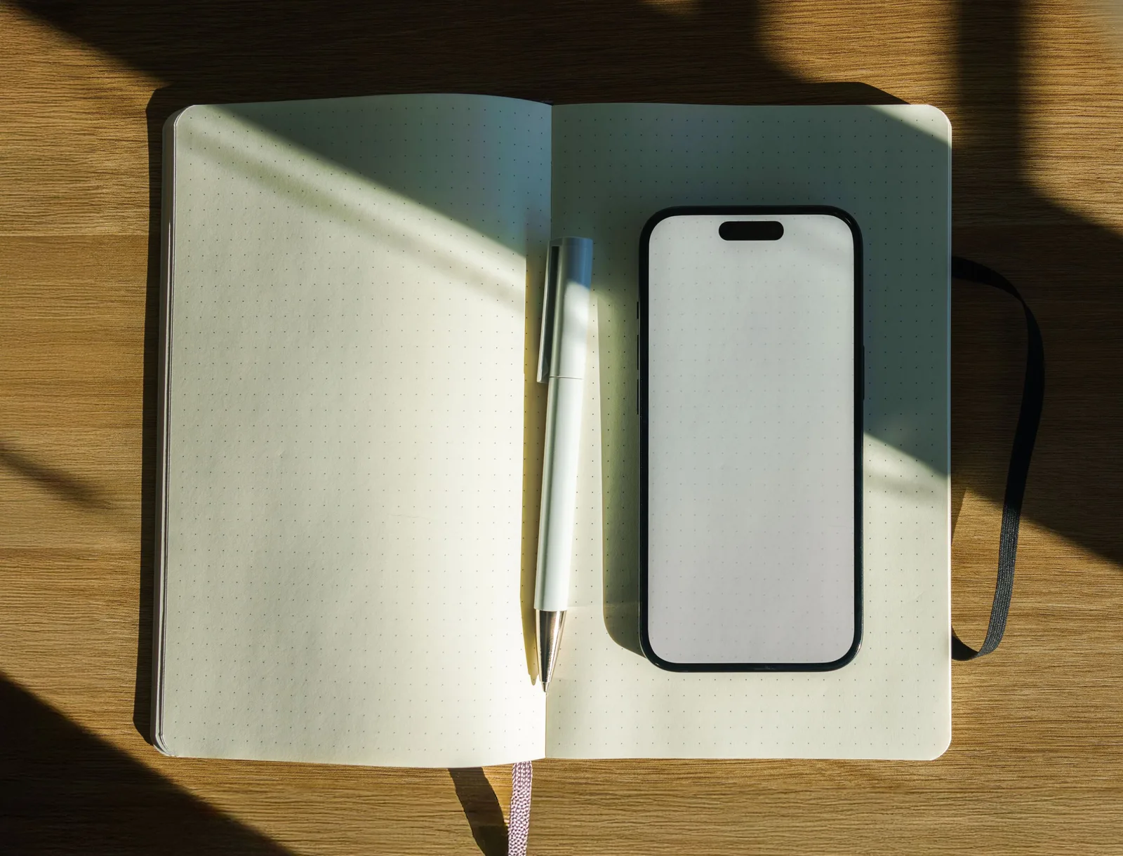 A minimalistic sunlit workspace featuring an open notebook, pen, and smartphone on a wooden desk. How to think about mobile notary operations