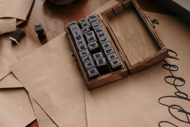 Vintage wooden box containing rubber alphabet stamps on brown paper envelopes. Mobile Notary Startup Costs: A Practical Budget