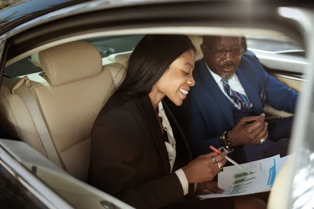Two business professionals in a car discussing strategies and analyzing charts. Remote Online Notary vs Mobile Notary: Which Costs Less?