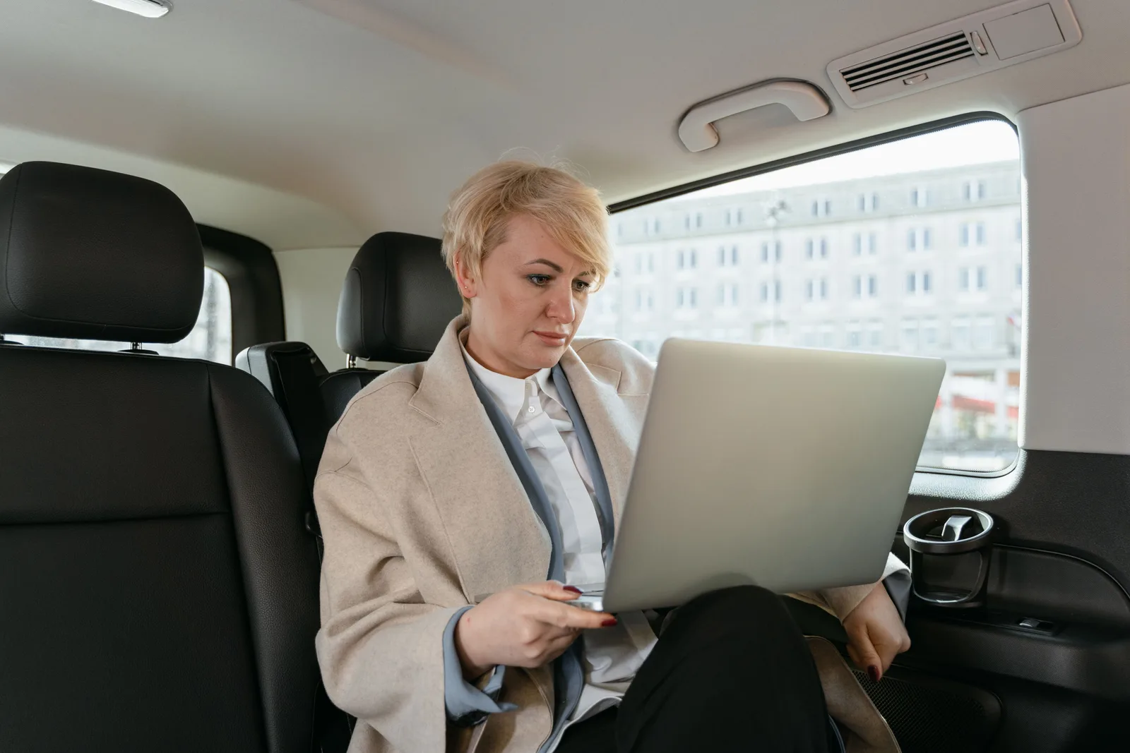 Professional woman working on a laptop inside a car, showcasing productivity on the move. How a mobile notary business finds permits and licenses before opening in 2027
