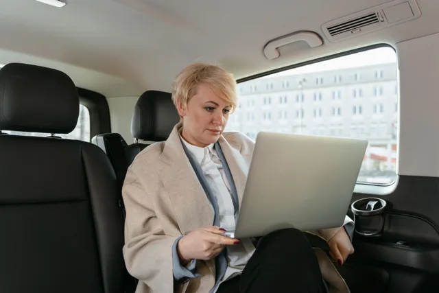 Professional woman working on a laptop inside a car, showcasing productivity on the move. How a mobile notary business finds permits and licenses before opening in 2027